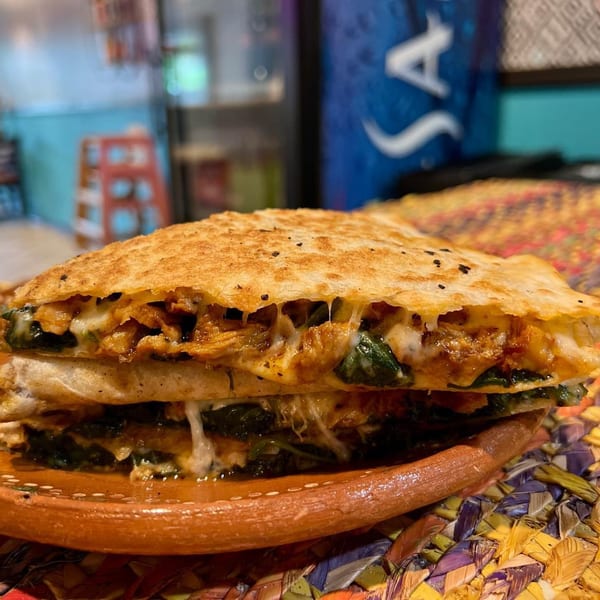 A cheesy, golden-brown quesadilla filled with chicken and spinach, served on a rustic plate.