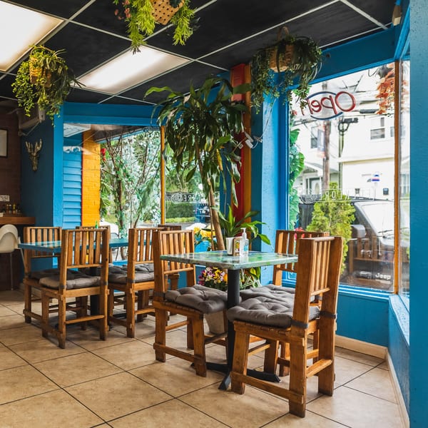 Folklore Artisanal Mexican restaurant interior with blue walls, wooden tables, and hanging plants.