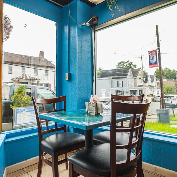 A Folklore Artisanal Mexican restaurant interior with a blue table and chairs next to a window.